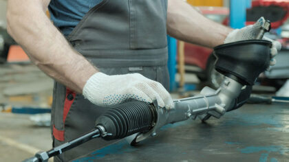 mechanic handles a power steering rack and pinion assembly