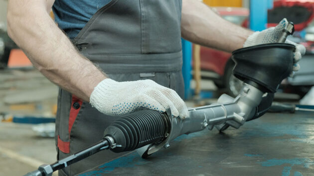mechanic handles a power steering rack and pinion assembly